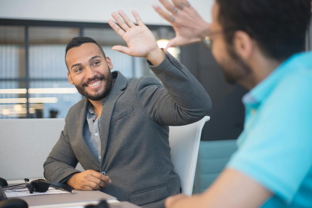 Deux hommes souriants, confiants et positifs qui se félicitent avec un high five