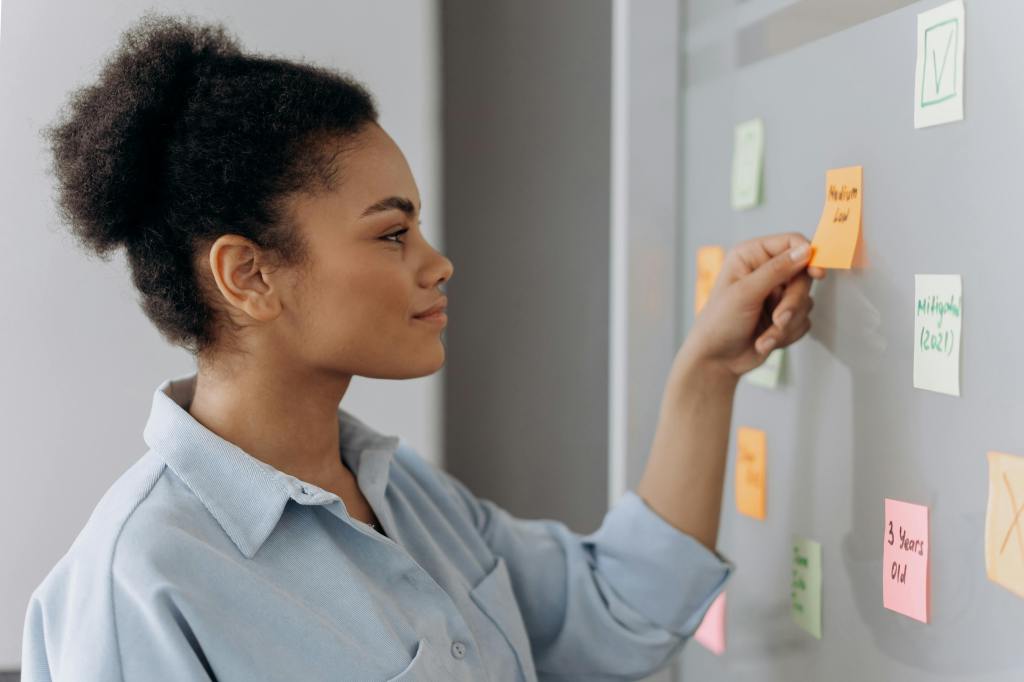 Femme face à son tableau de planification avec des post-its